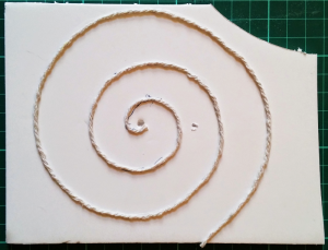 String spiral stuck onto foam board to act as a stamp for applying developer to the paper.