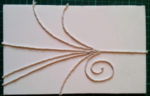 String trails stuck onto foam board to act as a stamp for applying developer to the paper.
